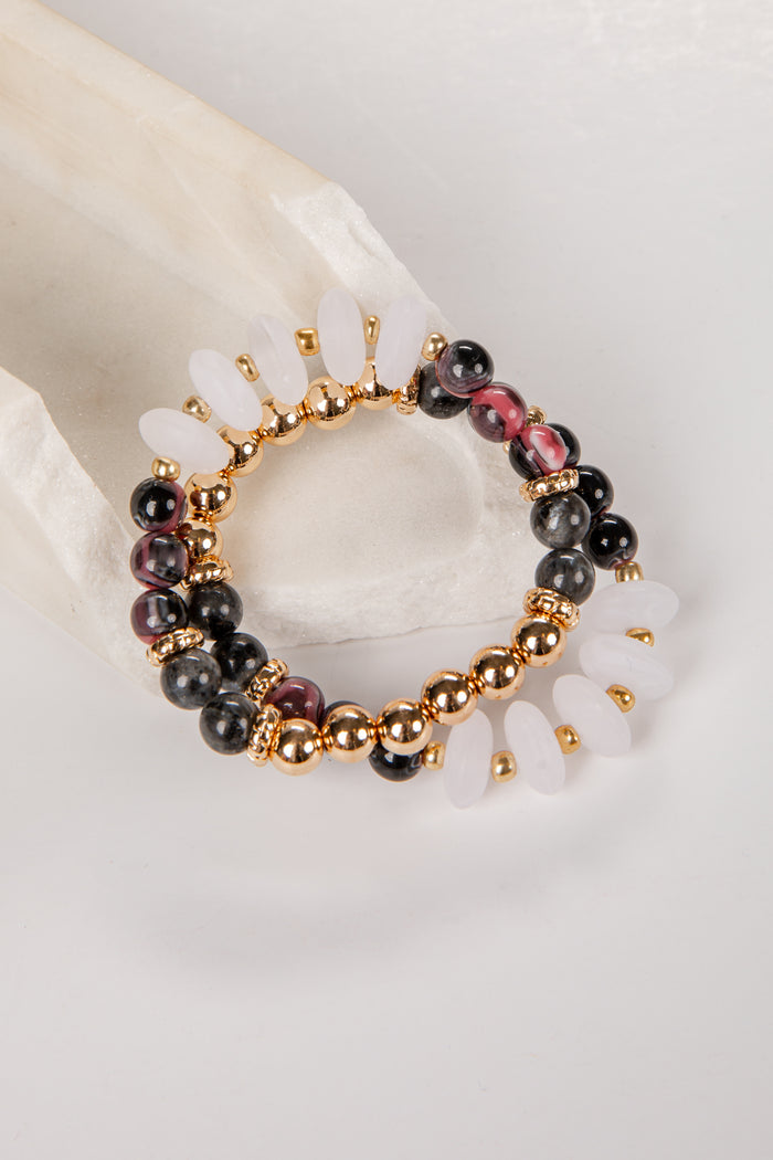 Beaded bracelet with gold accents on a white shell background