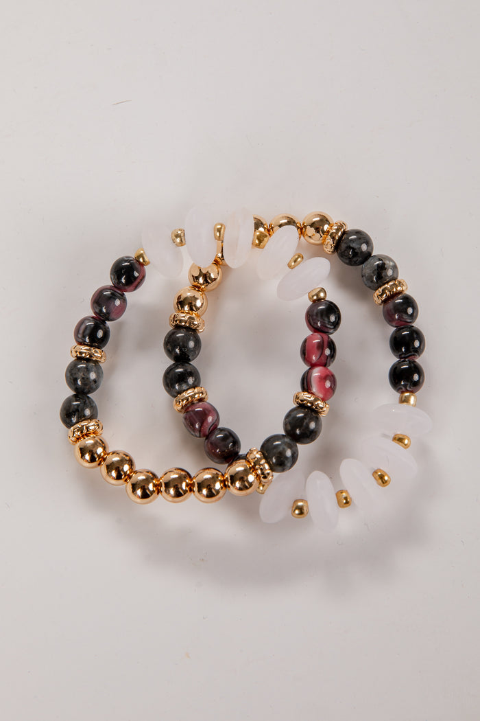 Pair of hoop earrings with black and gold beads on a light gray background