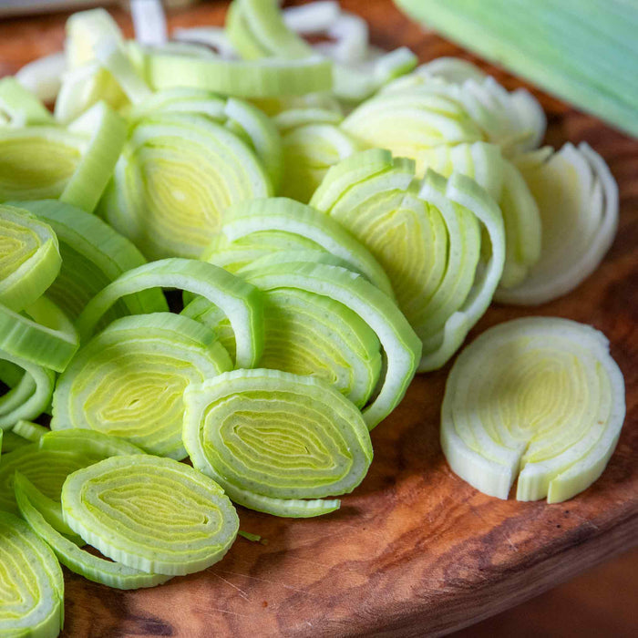 freshly chopped leeks on wooden chopping board.