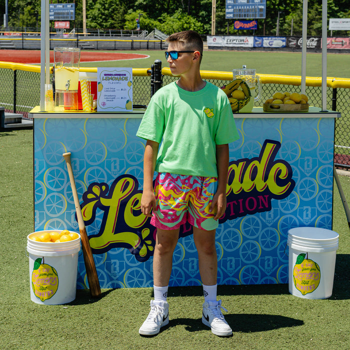 Youth model wearing multi-color youth shorts with "Lemon Burst" design