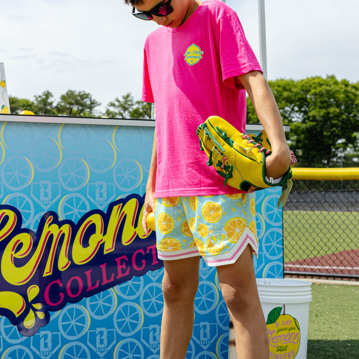 Youth model wearing blue youth shorts with "Lemon Squeeze Court" design