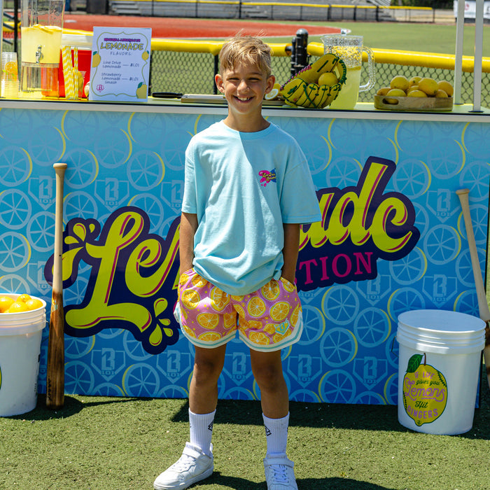 Youth model wearing pink youth shorts with "Lemon Squeeze Court" design