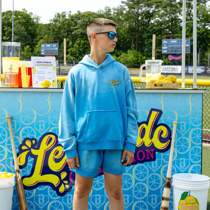 Youth model wearing blue youth shorts with "Lemonade Cup" design