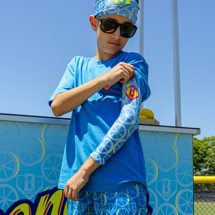 Youth model wearing blue youth arm sleeve with "Lemonade Splash" design