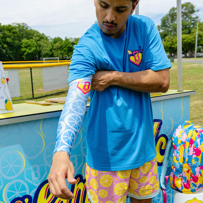 Youth model wearing blue youth arm sleeve with "Lemonade Splash" design