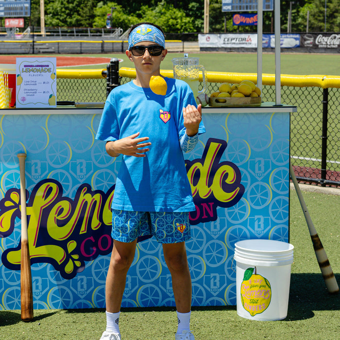 Youth model wearing blue youth shorts with "Lemonade Splash" design