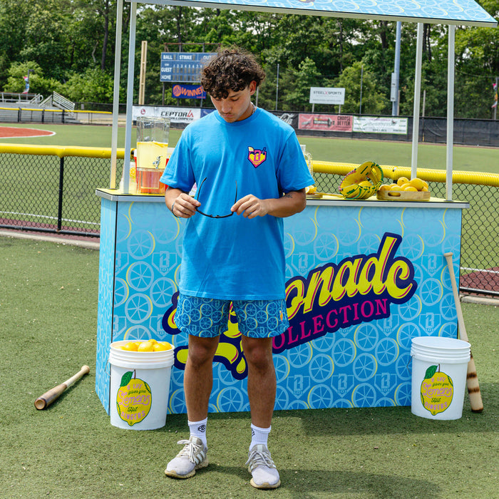 Adult model wearing blue graphic tee with "Lemonade" design