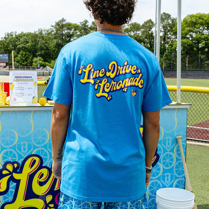 Adult model wearing blue graphic tee with "Lemonade" design