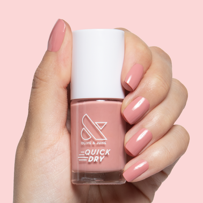 Lovely dusty rose gel polish on natural nails with a smooth glossy finish held against soft pink background