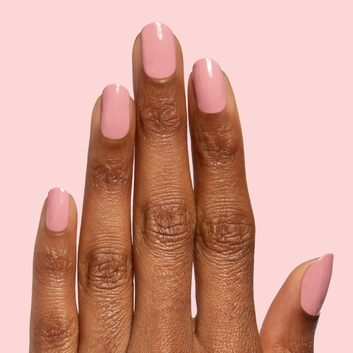 Lovely gel polish in soft dusty rose shade on natural nails with a smooth glossy quick dry finish against pale pink background