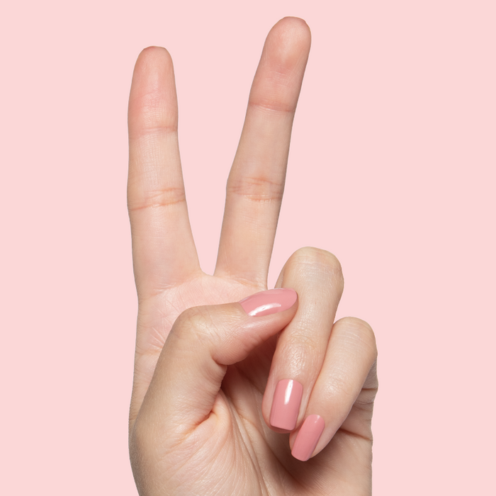 Lovely dusty rose gel polish on natural nails with a smooth glossy finish against soft pink background