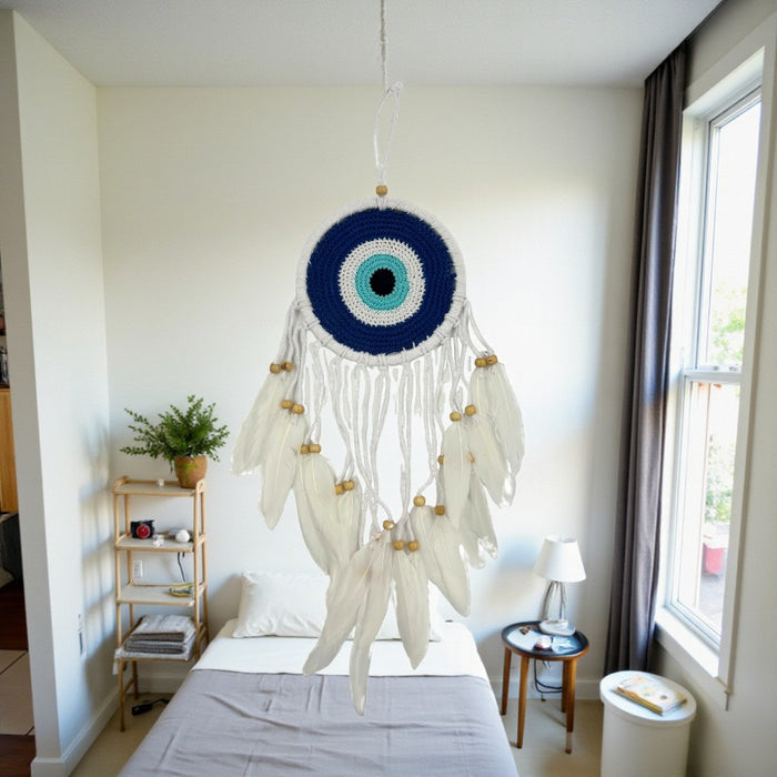 Decorative dreamcatcher hanging in a bedroom with a bed and window in the background.