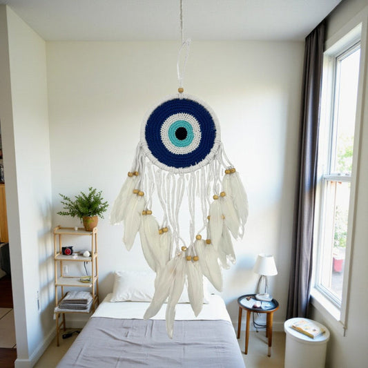 Decorative dreamcatcher hanging in a bedroom with a bed and window in the background.