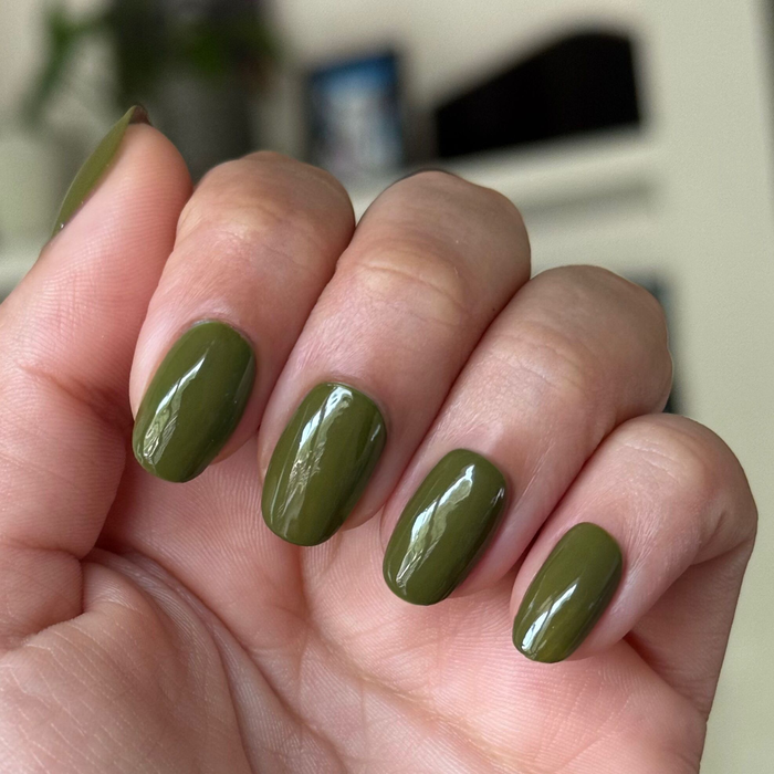 Hand with nails painted in glossy Mossy gel polish showing fresh quick dry manicure on natural nails