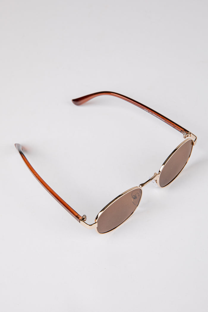 Sunglasses with gold frame and brown lenses on a white background