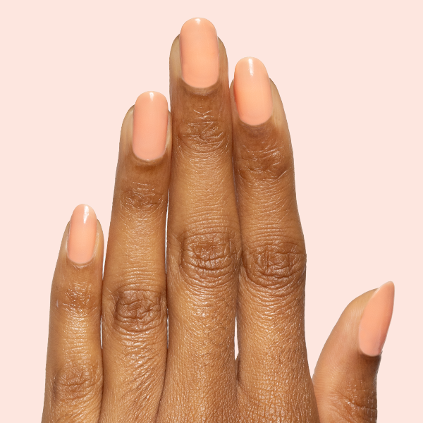 Hand with Peeptoe sheer warm peach glossy gel polish manicure on natural medium-length nails against pale pink background