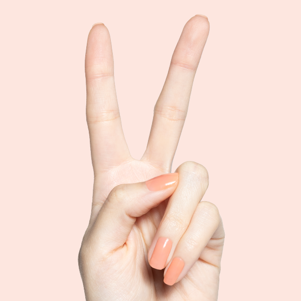 Hand showing peace sign with Peeptoe warm peach gel polish manicure on medium-length natural nails against soft peach background
