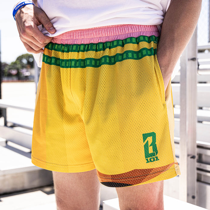 Youth model wearing yellow youth shorts with “Pencil” design