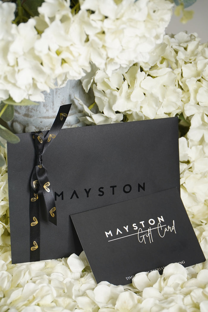 Mayston gift card packaging on a bed of white flowers