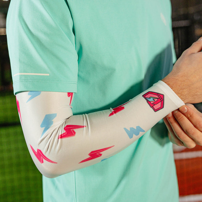 Close-up of the lightning arm sleeve on a player's bent arm showing the pink and blue lightning bolt print and pink BL101 logo near the wrist against a mint green shirt