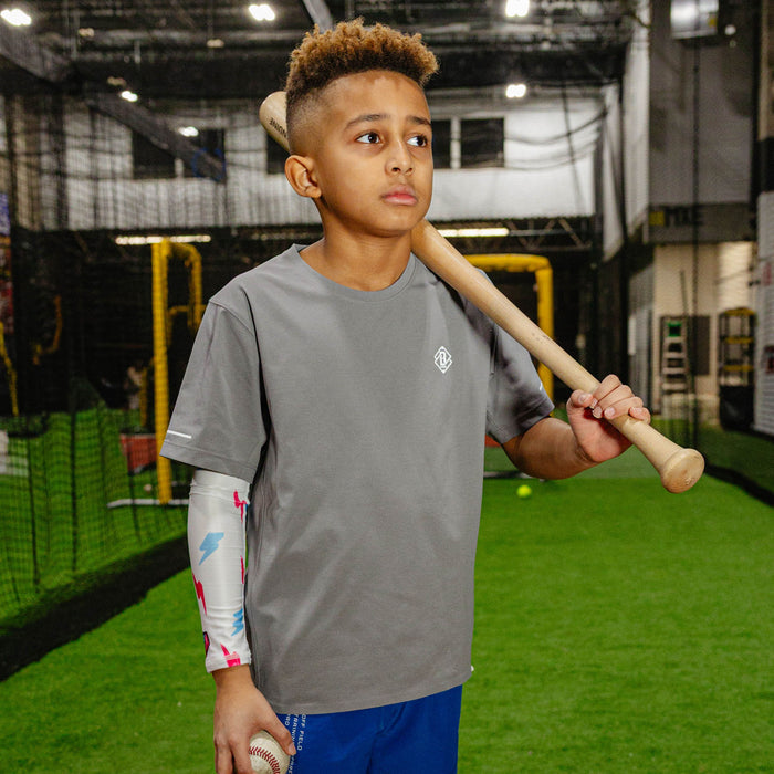 Youth model wearing white and pink and blue Rain Delay Lightning Arm Sleeve youth sleeve