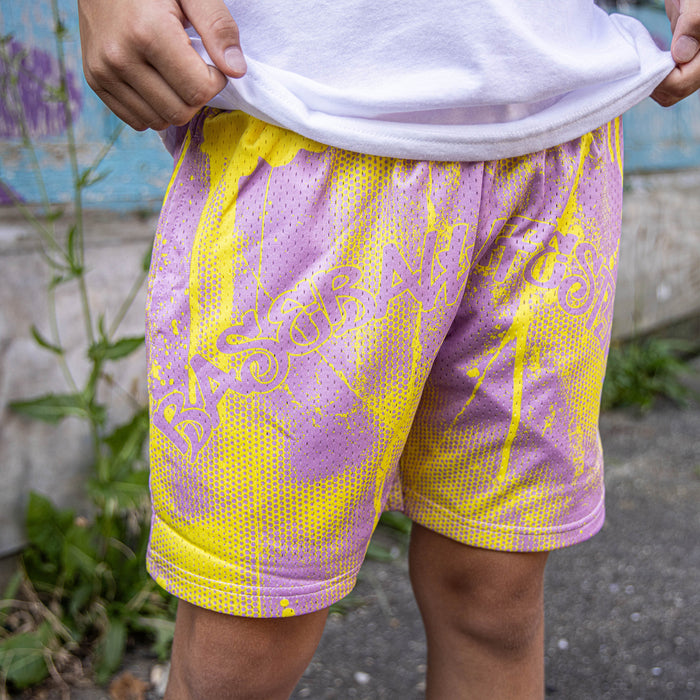 Youth model wearing pink and yellow Retro Graffiti youth shorts