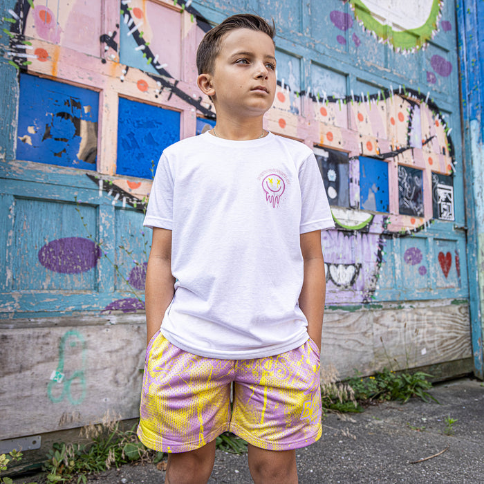 Youth model wearing pink and yellow Retro Graffiti youth shorts