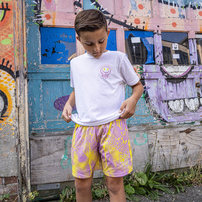 Youth model wearing pink and yellow Retro Graffiti youth shorts