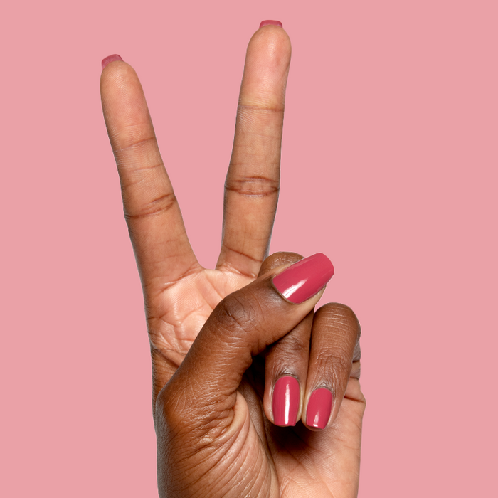 Hand with natural nails painted in glossy Roar quick dry gel polish showing confident manicure on pink background