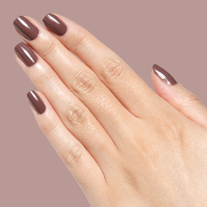 Hand with natural nails painted in warm silky Sable gel polish showing smooth quick dry manicure on neutral background