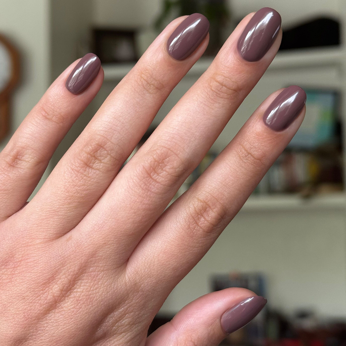 Hand with natural nails painted in glossy Sable gel polish showing smooth long-lasting manicure indoors