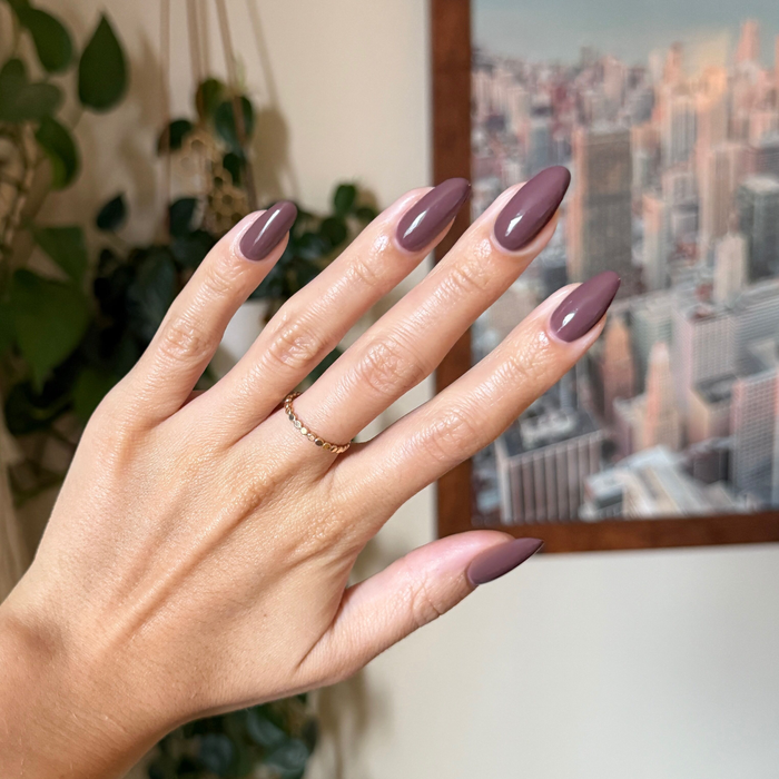 Hand with almond shaped nails painted in smooth Sable gel polish showing a chic quick dry manicure indoors