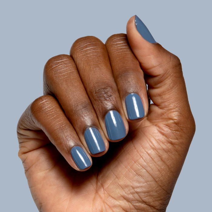 Hand with nails painted in Slate midtone blue gel polish showing smooth glossy quick dry manicure