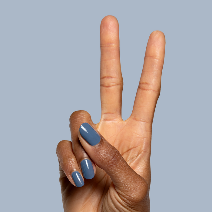 Hand showing peace sign with nails painted in smooth glossy quick dry Slate gel polish against grey background