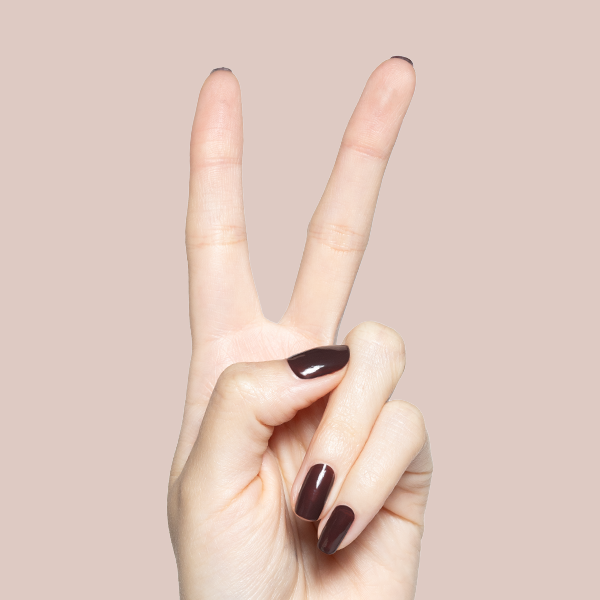 Hand showing peace sign with glossy Spressotini quick-dry gel polish manicure in deep coffee brown on short nails against beige background