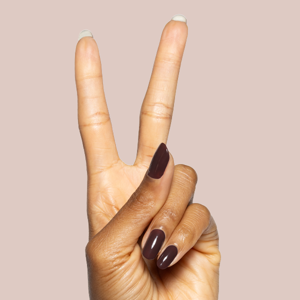Hand showing peace sign with glossy Spressotini gel polish manicure in dark coffee brown on natural nails against beige background
