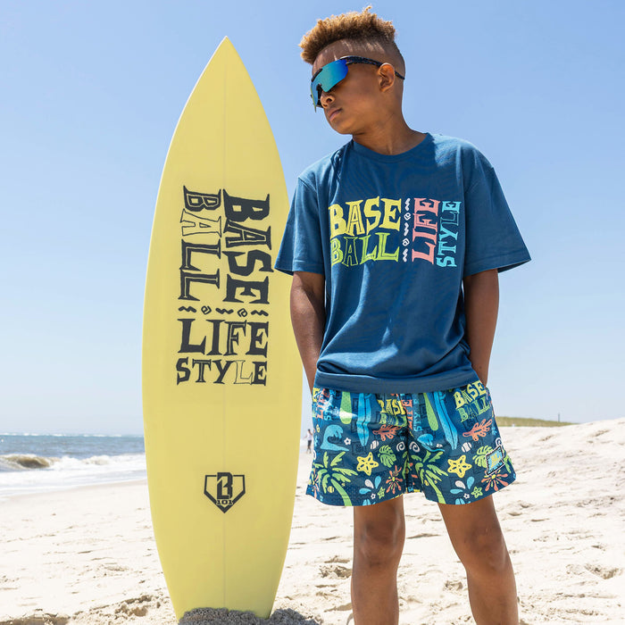 Youth model wearing multi-color youth shorts with "Surfside Slugger" design