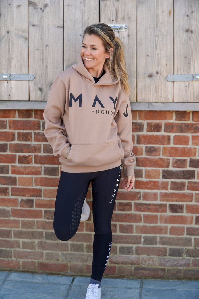 A person wearing a beige brown hoodie with 'MAY' printed on the front in large letters, paired with black leggings and white shoes, standing in front of a wooden background.
High quality luxurious 100% cotton. wrap around bold logo. soft, cozy and  warm. Hoodie, jumper sweatshirt. everyday wear. casual and smart