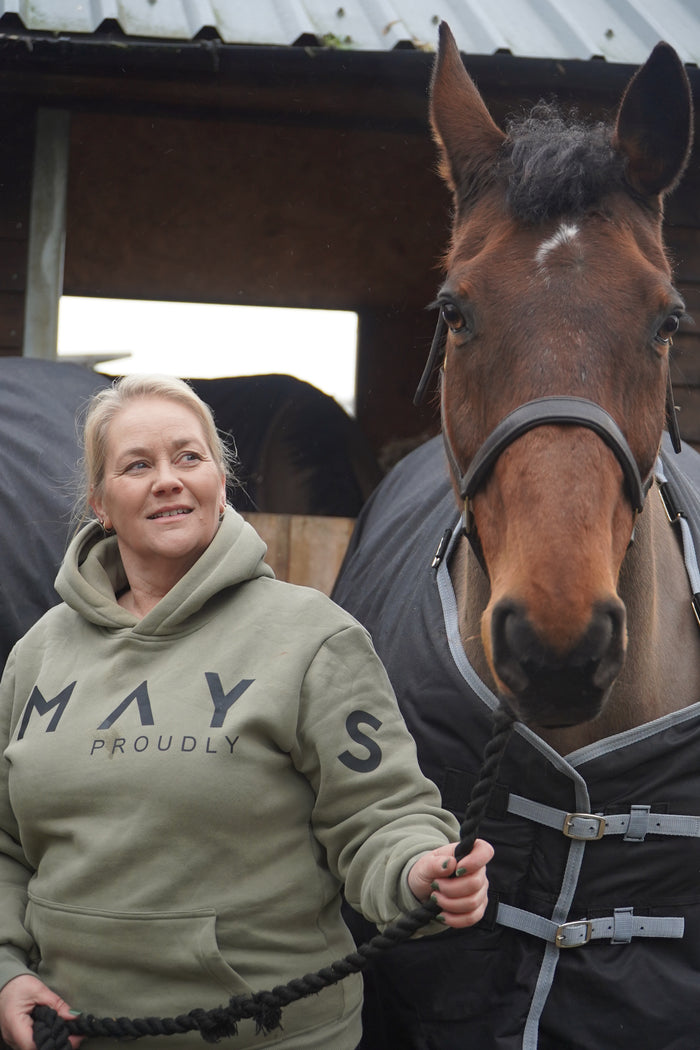 Person wearing a hoodie with text, standing next to a horse in an indoor setting. A person wearing a green hoodie with a large hood, standing next to a white horse. The person is wearing black pants and black boots, and the hoodie has the word 'Equestrian' written on it.
High quality luxurious 100% cotton. wrap around bold logo. soft, cozy and  warm. Hoodie, jumper sweatshirt. everyday wear. casual and smart
