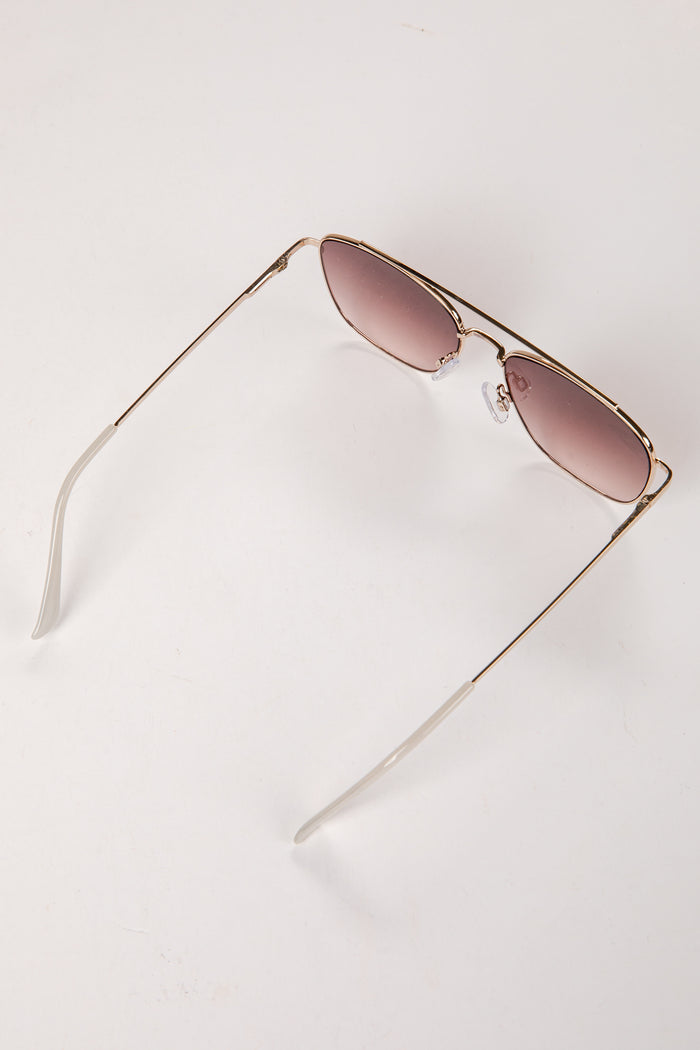 Gold-framed sunglasses with pink lenses on a white background