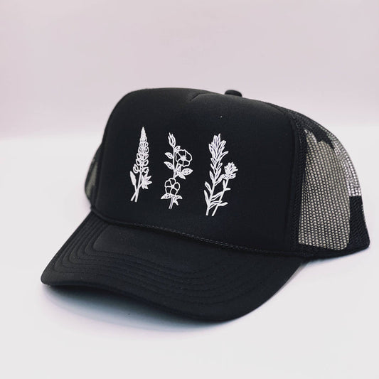 Black Wildflowers adult trucker hat by Made of Mountains featuring a floral embroidered design and adjustable mesh back.